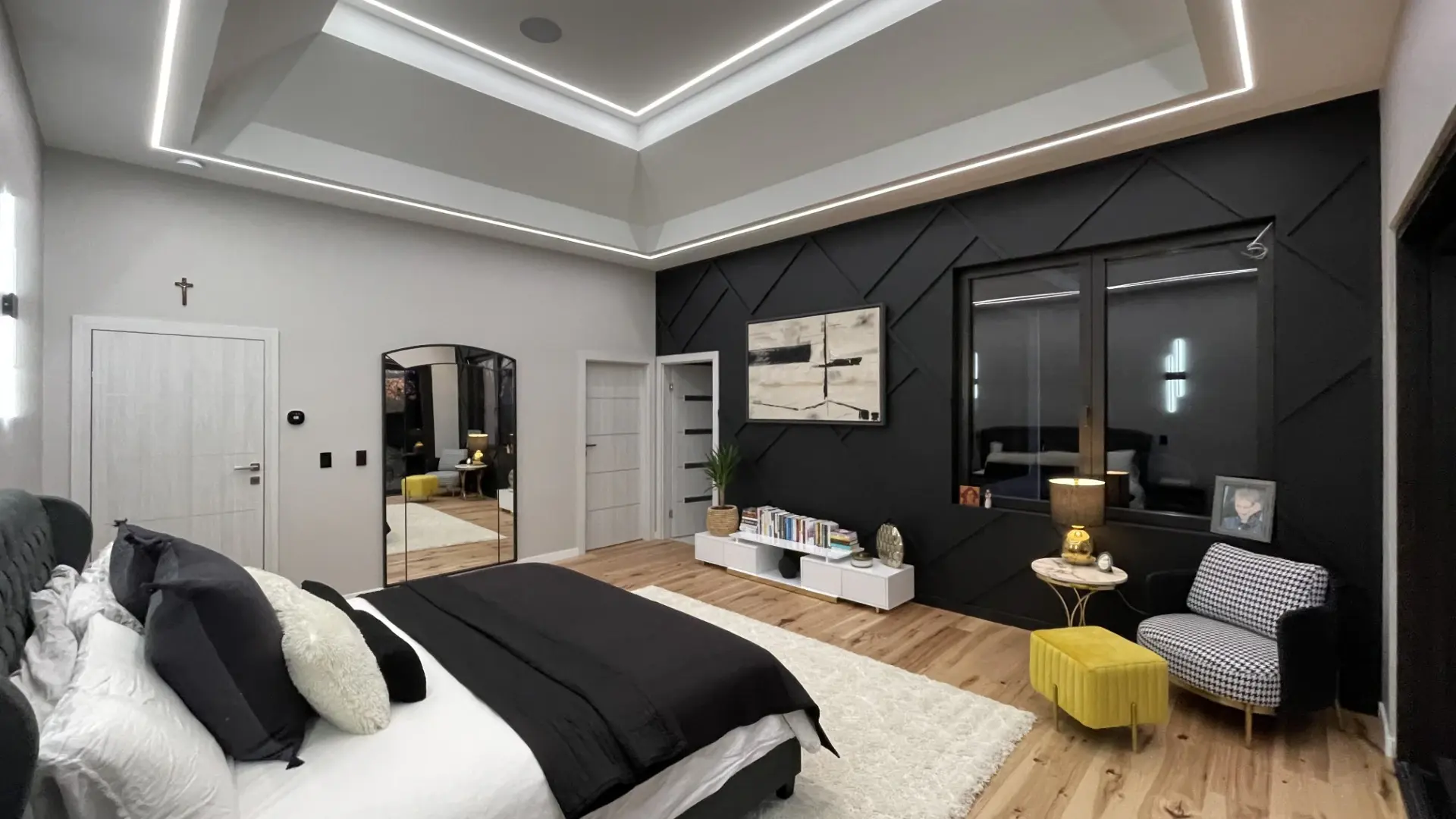 Bedroom with a dark accent wall, custom joinery and hardwood flooring